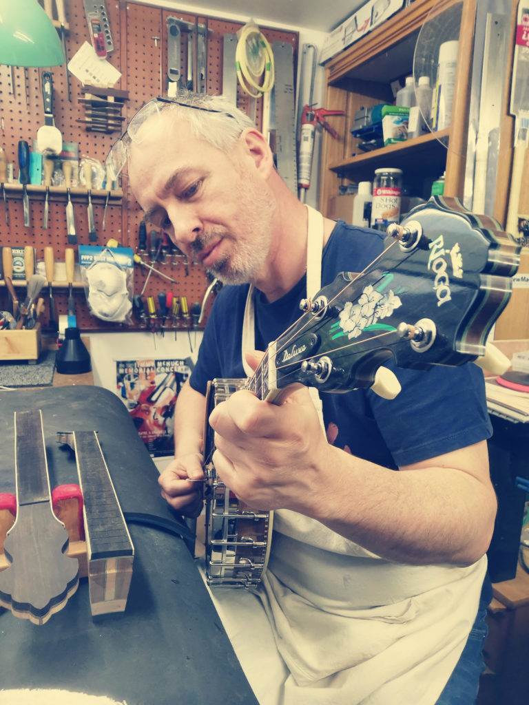 photo of John McClenaghan testing out one of his handmade open-back tenor banjos